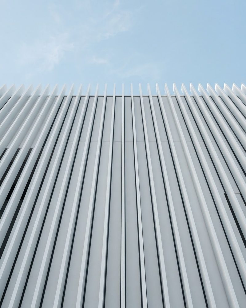 White architectural facade with vertical fins against a blue sky
